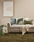 Beige sofa with decorative pillows and a blanket in a living room setting.