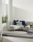 Modern outdoor seating area with a curved sofa, cushions, and a small table.