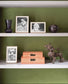 Shelving unit with decorative items against a green wall, featuring the brand 'Addison Ross London'.