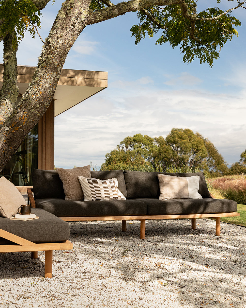 Outdoor sofa with cushions under a tree in a scenic setting