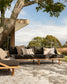 Outdoor sofa with cushions under a tree in a scenic setting