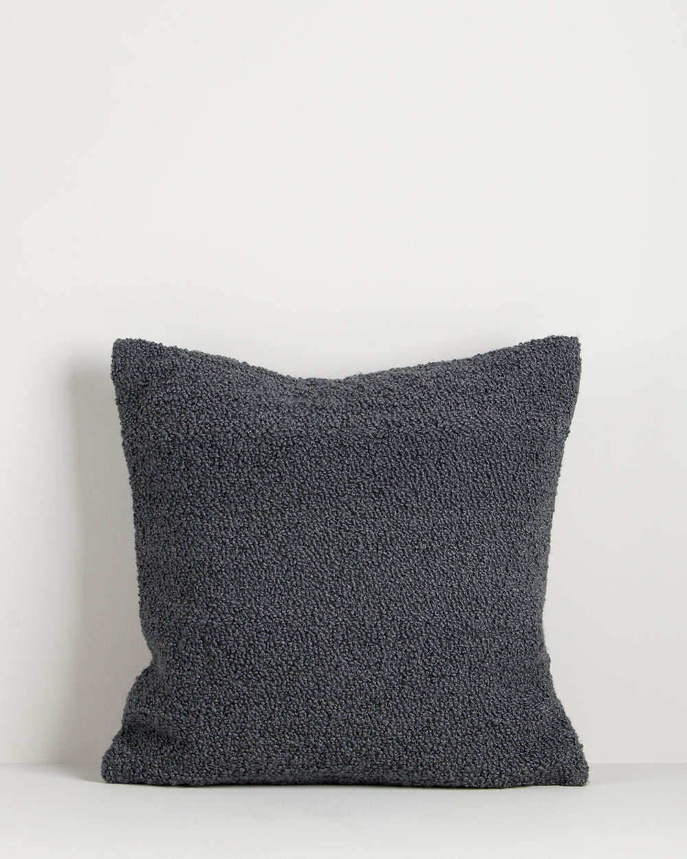Dark gray textured pillow on a light gray background