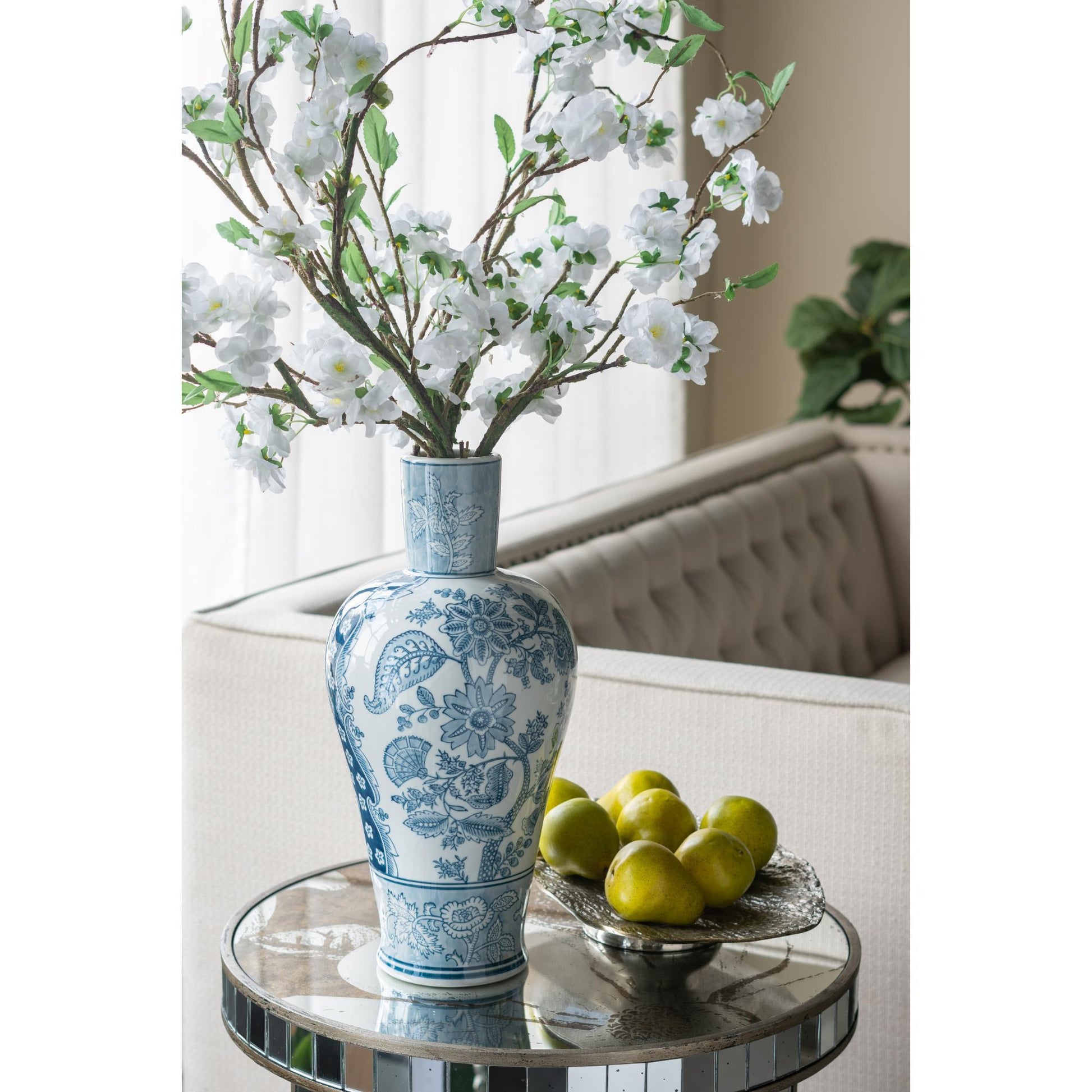 Decorative blue and white vase with floral arrangement on a table.