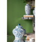 Blue and white ceramic jar with a green wall in the background