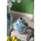 Blue and white ceramic jar with floral patterns on a stack of books, with another similar jar in the background.