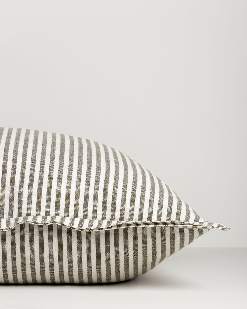 Striped pillow with gray and white stripes on a light gray background