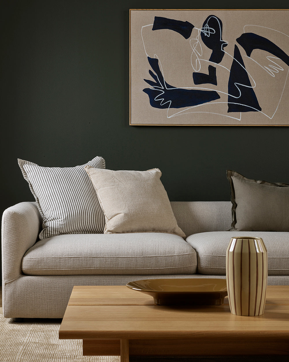 Modern living room with a gray sofa, abstract art, and wooden coffee table.