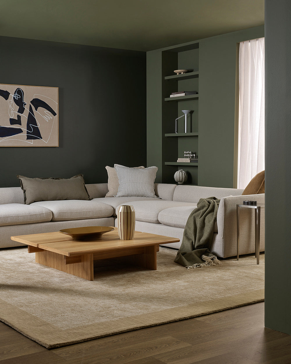 Modern living room with a gray sectional sofa, wooden coffee table, and abstract art on the wall.
