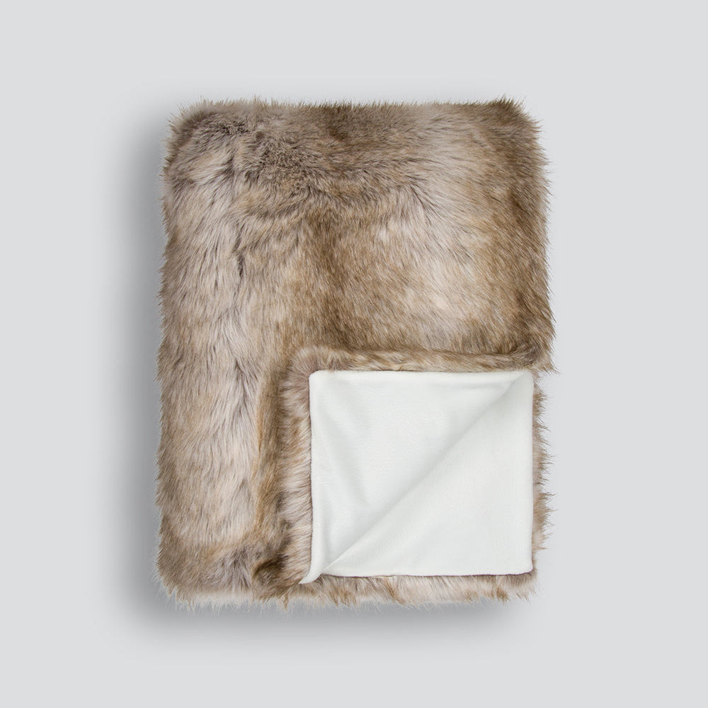 Faux fur throw blanket with white interior on a light gray background