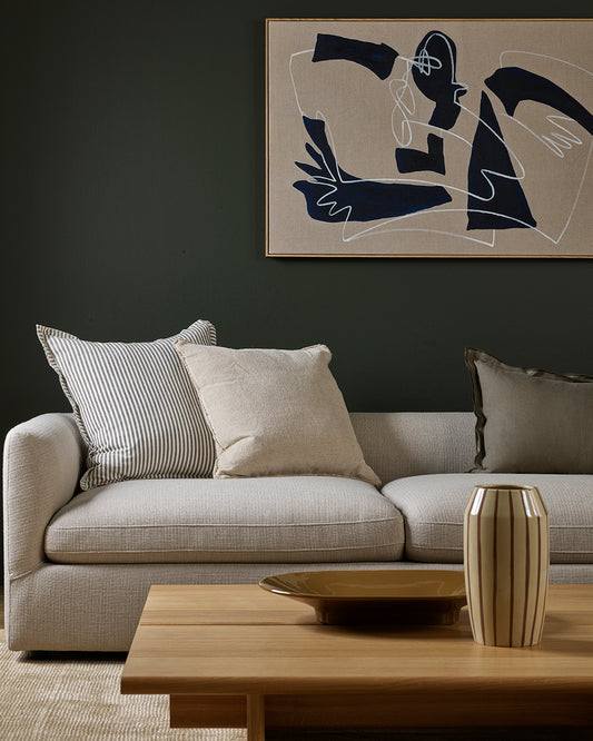 Modern living room with a gray sofa, abstract art, and wooden coffee table.