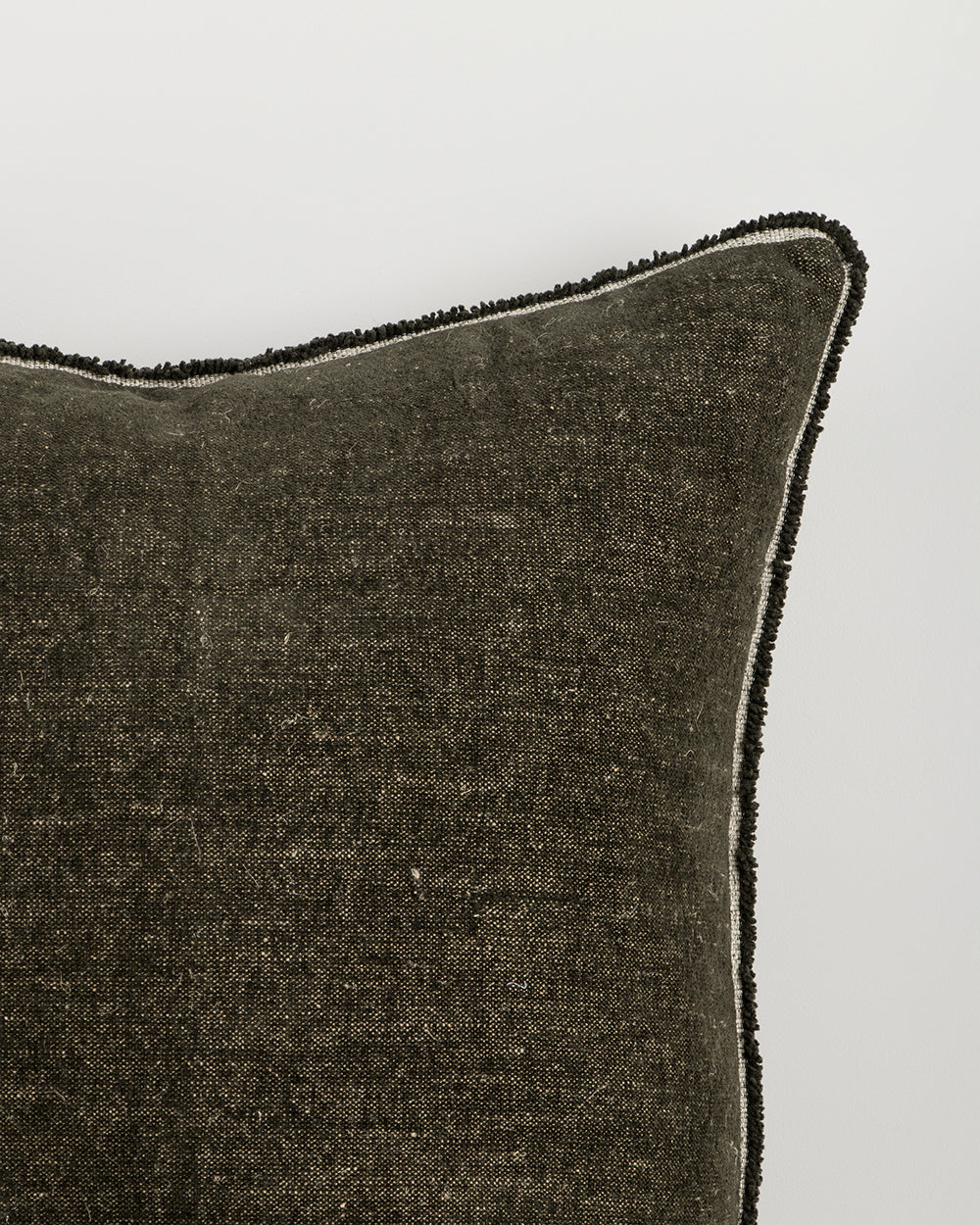 Textured dark gray pillow with decorative trim on a light gray background