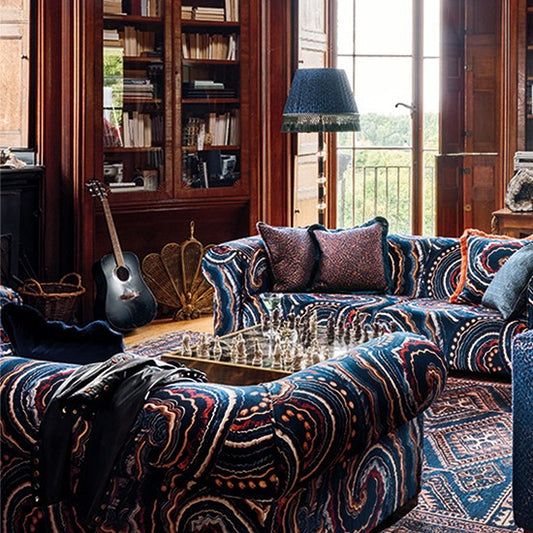 Maximalist lounge with old fashioned oak verandah shutters and oak furniture complemented by two sofas covered in the swirly fantasia fabric