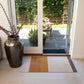 Decorative vase with branches on a rug in front of a glass door leading to a garden.