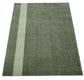 Green rug with a white stripe on a white background