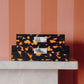 Set of tortoiseshell-patterned boxes on a marble surface with a striped wall background