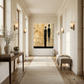 oversized abstract art on the wall at the end of a pale hallway featuring male and female silhouettes with bronze and glass wall sconces, beige linen and wood bench, wooden table