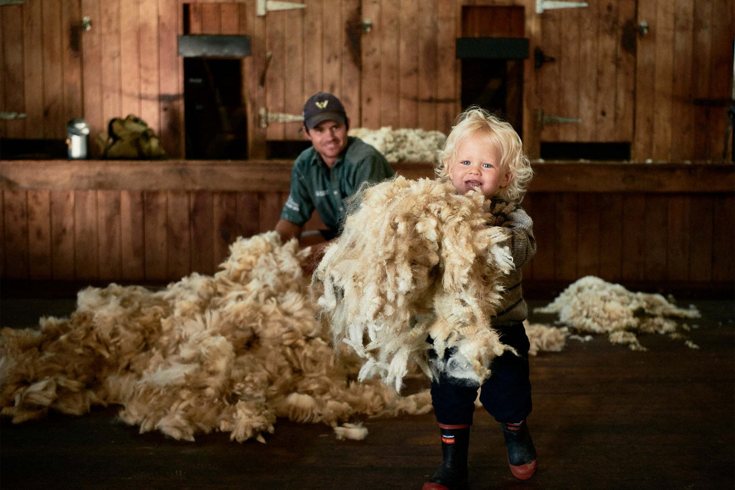 Two people in a barn with large amounts of wool