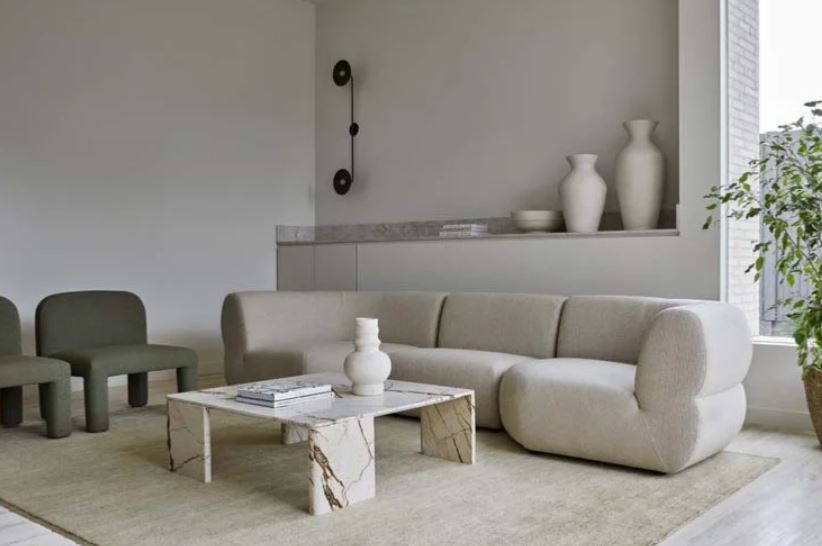 Hugo Arc occasional chair in saltbush with a large rounded cream sofa in a lounge with cream vases and walls