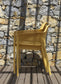 nardi net chair in mustard on wooden deck beside a stacked stone wall