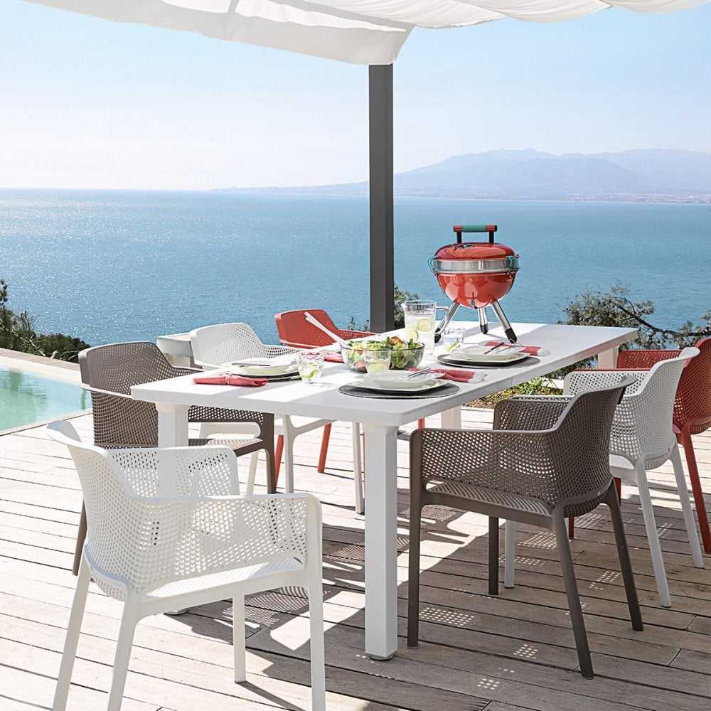 net outdoor chairs in white, taupe and coral around a white table over looking the sea