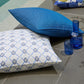 Elba cushion in white and blue with a blue cushion by the pool