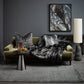 Alaskan Wolf imitation fur throw from heirloom in a lifestyle shote, grey scene with bird picture on the wall and Alaskan Wolf cushion on a green velvet sofa with a grey stone looking lamp and silver coffee table