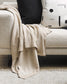 Carmel throw in fawn draped on a cream boucle sofa with a white and black cushion