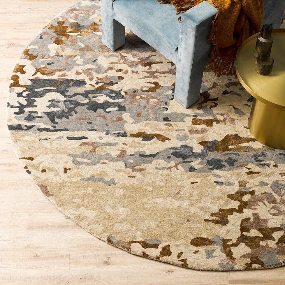 Fleur Multi Rug from Mulberi, abstract pattern of gold, greys, beignes and creams with a glue chair and gold coffee table