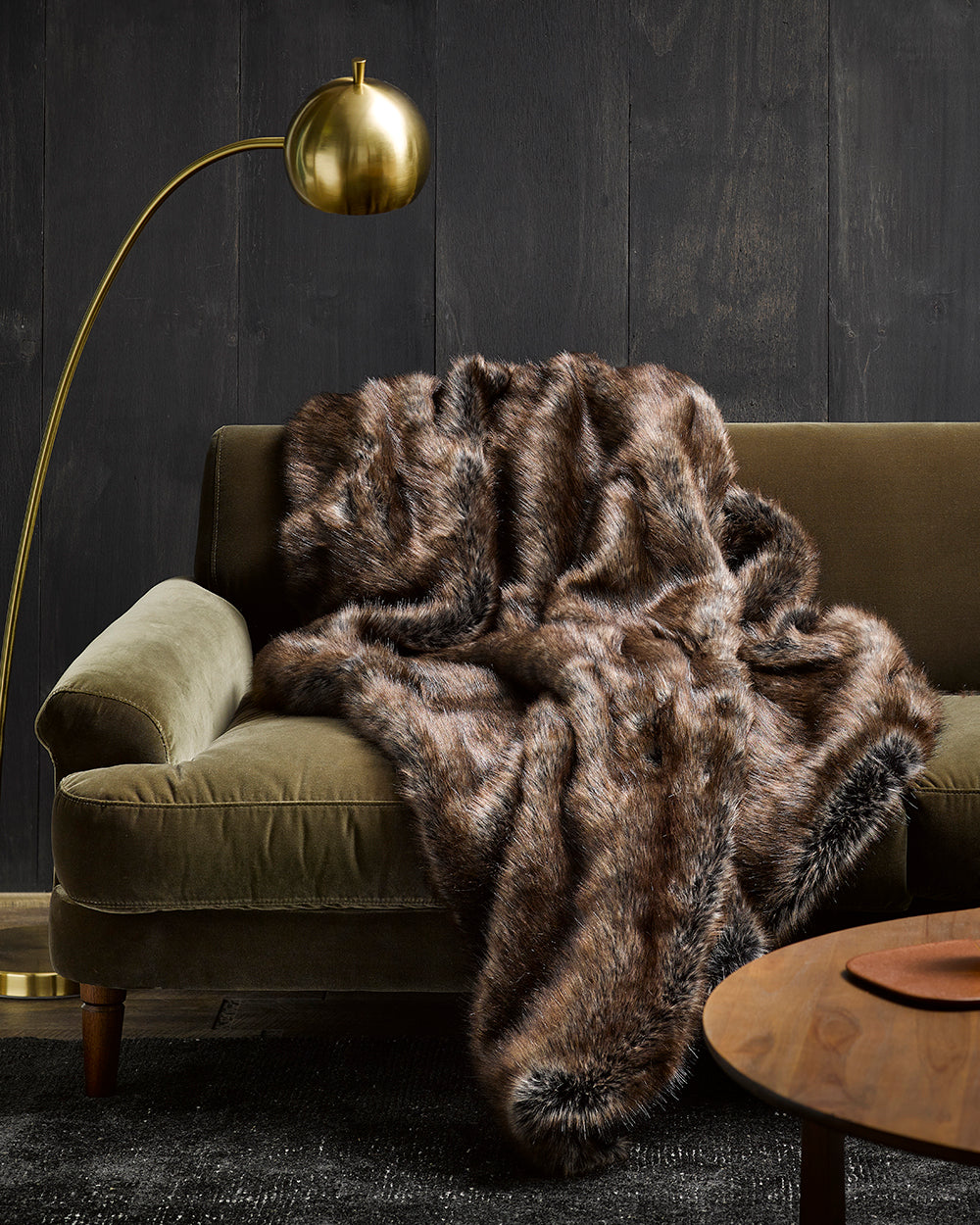 Imitation faux fur throw in Husky on green velvet sofa with gold light and wooden cofee table