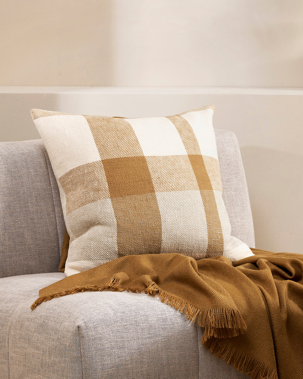 Jefferson cushion cumin on a cream sofa with a  cumin coloured throw