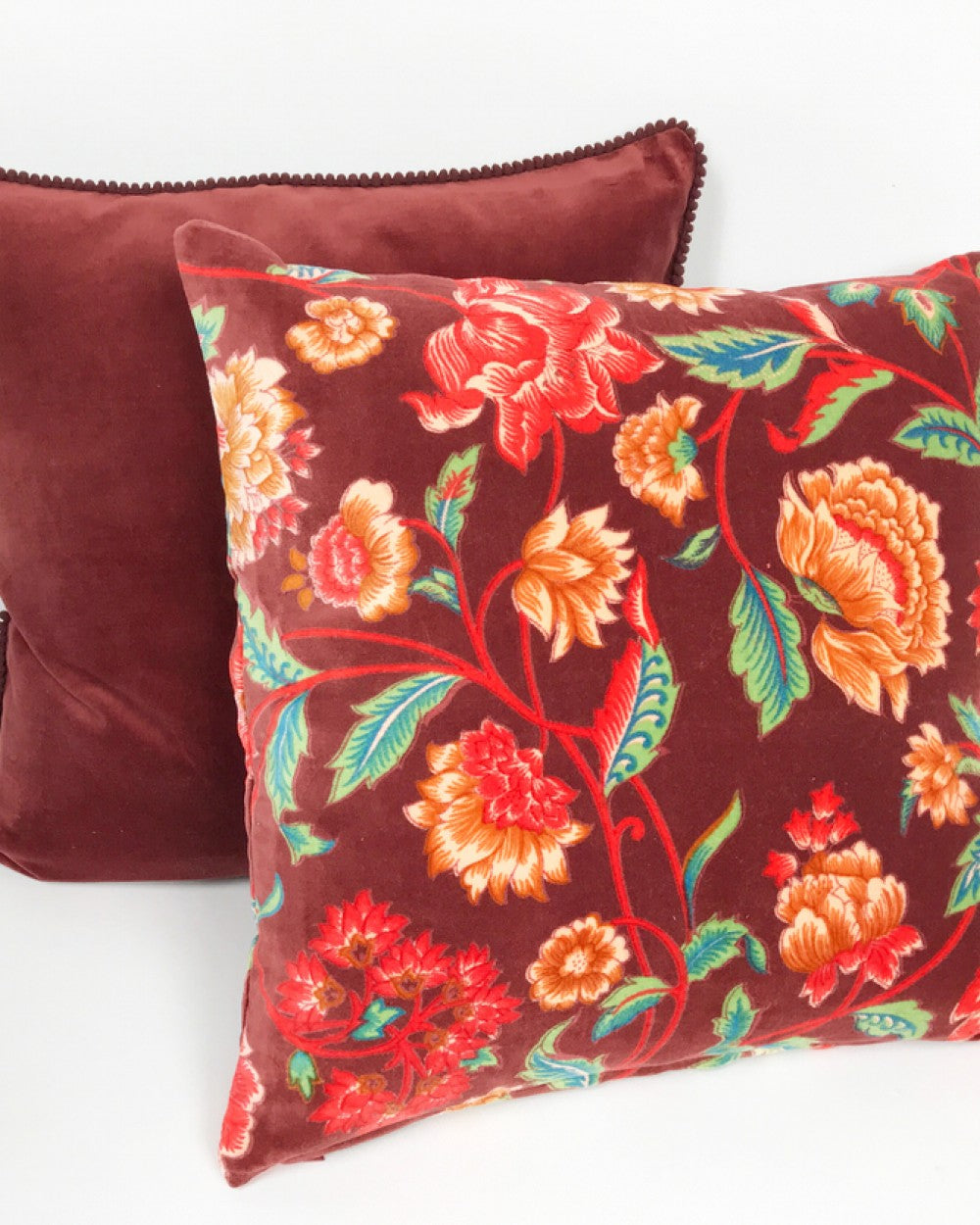 Red Lily velvet cushion with bright botanicals on a red rust background