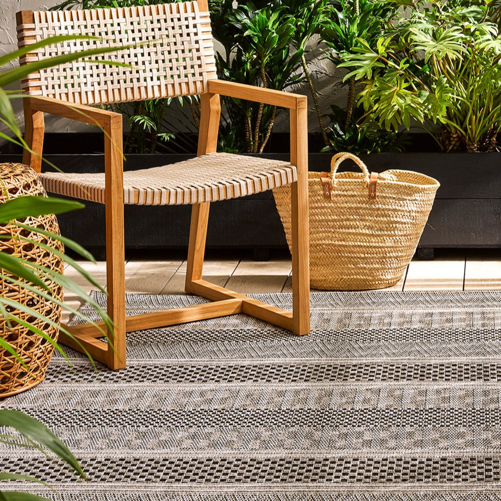 Peru outdoor rug with a chair and basket alongside with foliage in the background