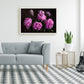 pink peonies floral wall art in a white frame above a grey modern sofa with wooden legs on a grey and white diamond checked floor. Alongside are 2 gold wire side tables with reen plants in white bots and a black wire candle holde ron the floor