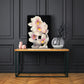 white orchid print on a wooden table with a dark blue panel wall behd it